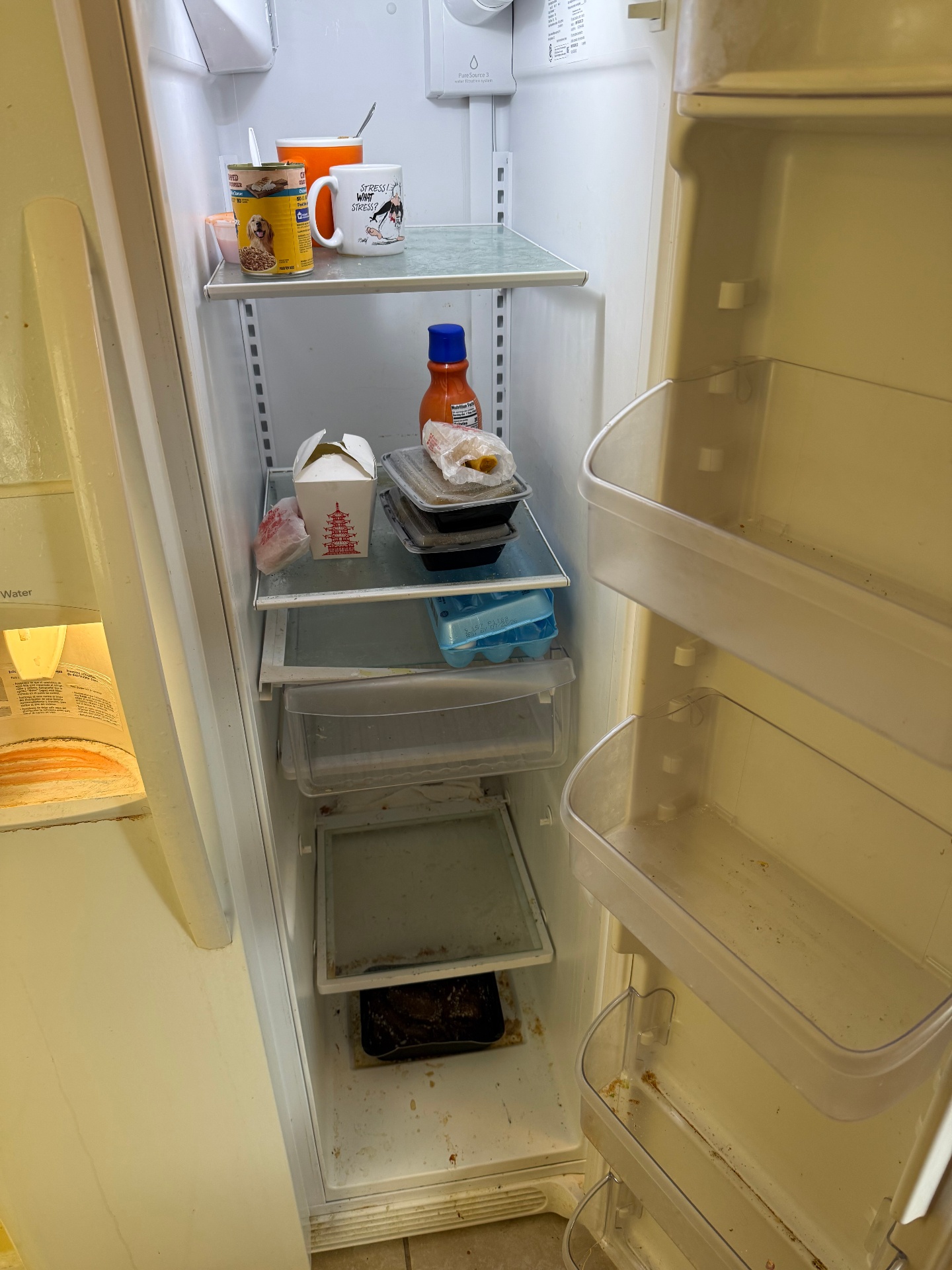 Refrigerator with old containers, spills, and residue on the shelves